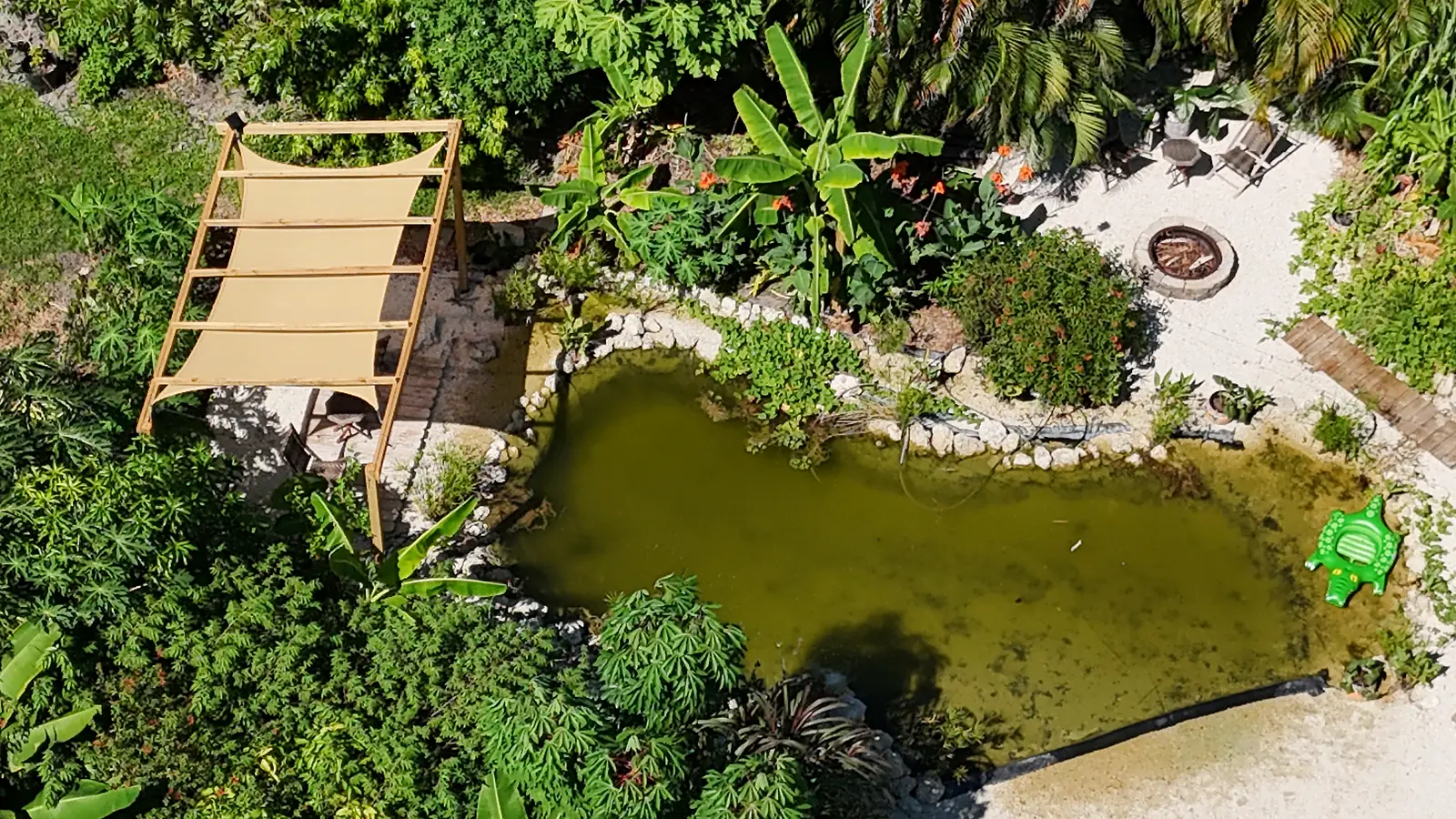 Aerial close-up of the lagoon, shade sail and firepit surrounded by food forest, September 2026