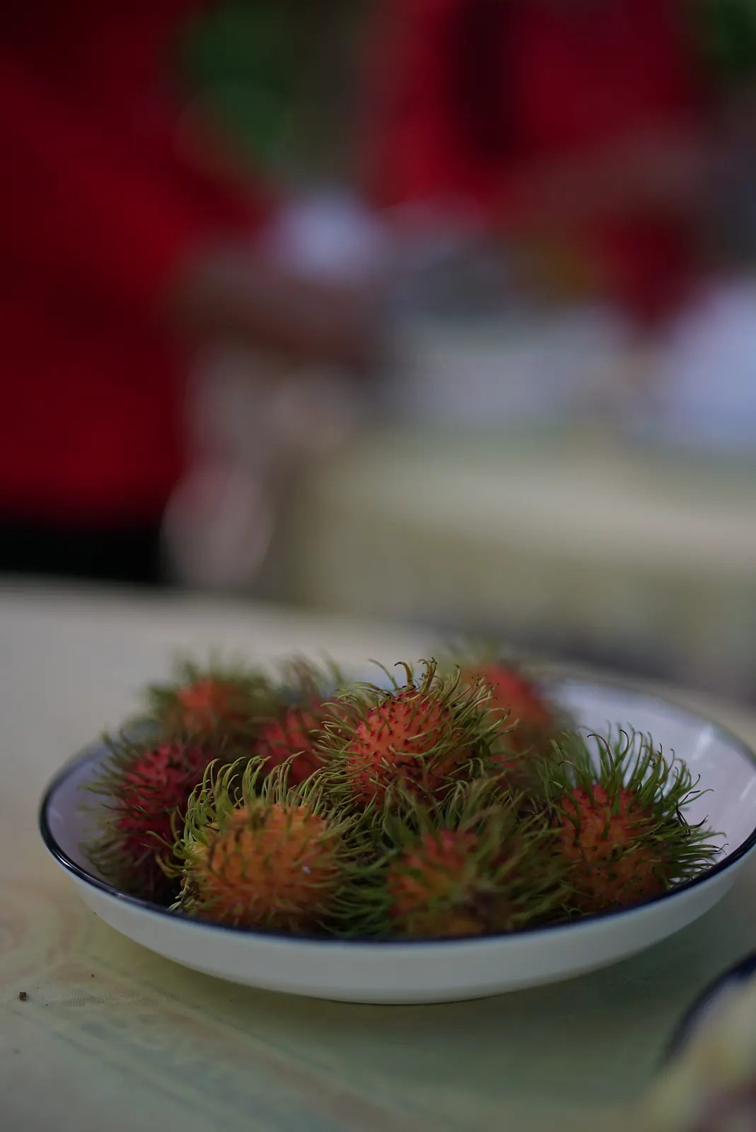A bowl of fresh red rambutan at a market table