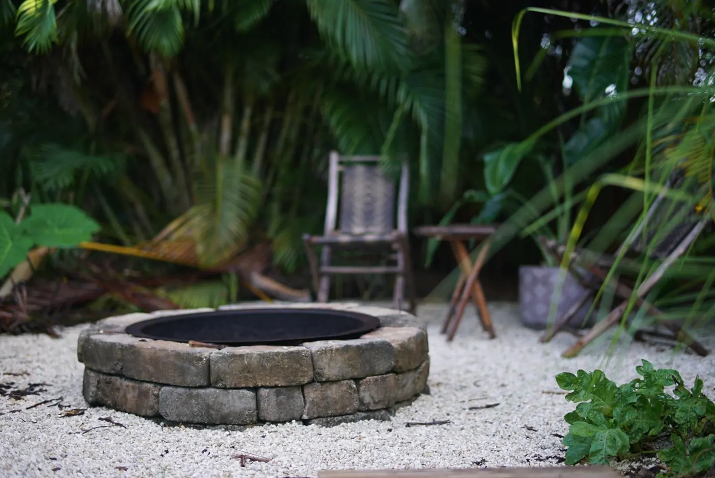 Stone firepit garden room on white gravel surrounded by palms in Bradenton