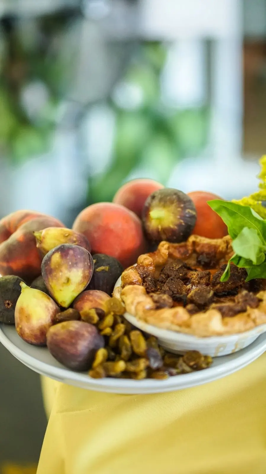 A plate of fresh figs and peaches with a fruit tart at a harvest gathering