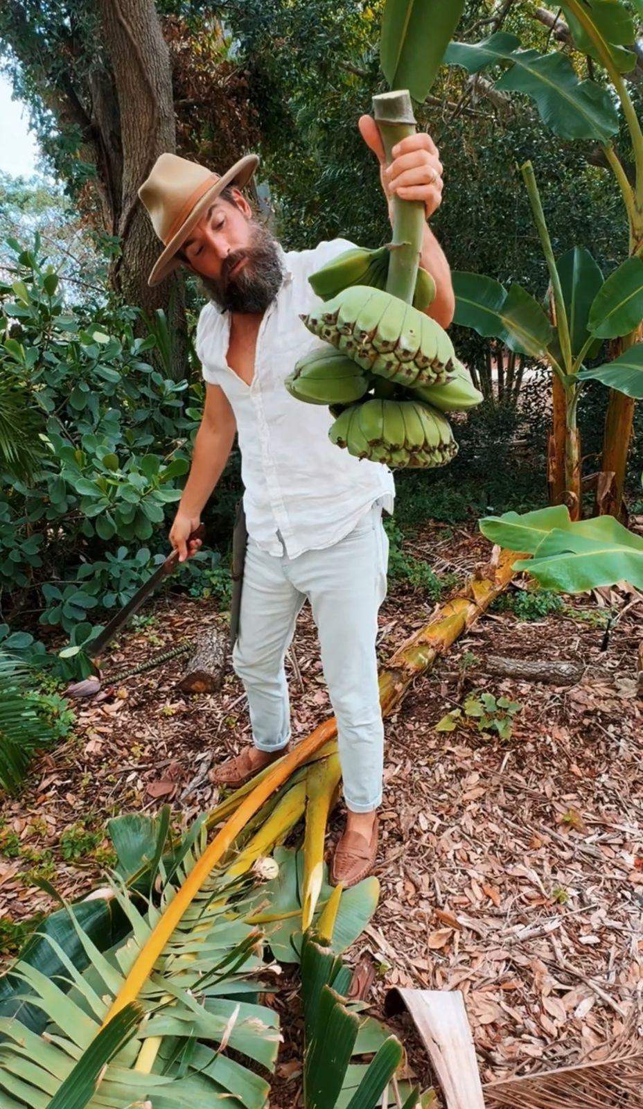 Matthew Nadu, the Fruit Hunter, holding a freshly cut banana bunch with a machete