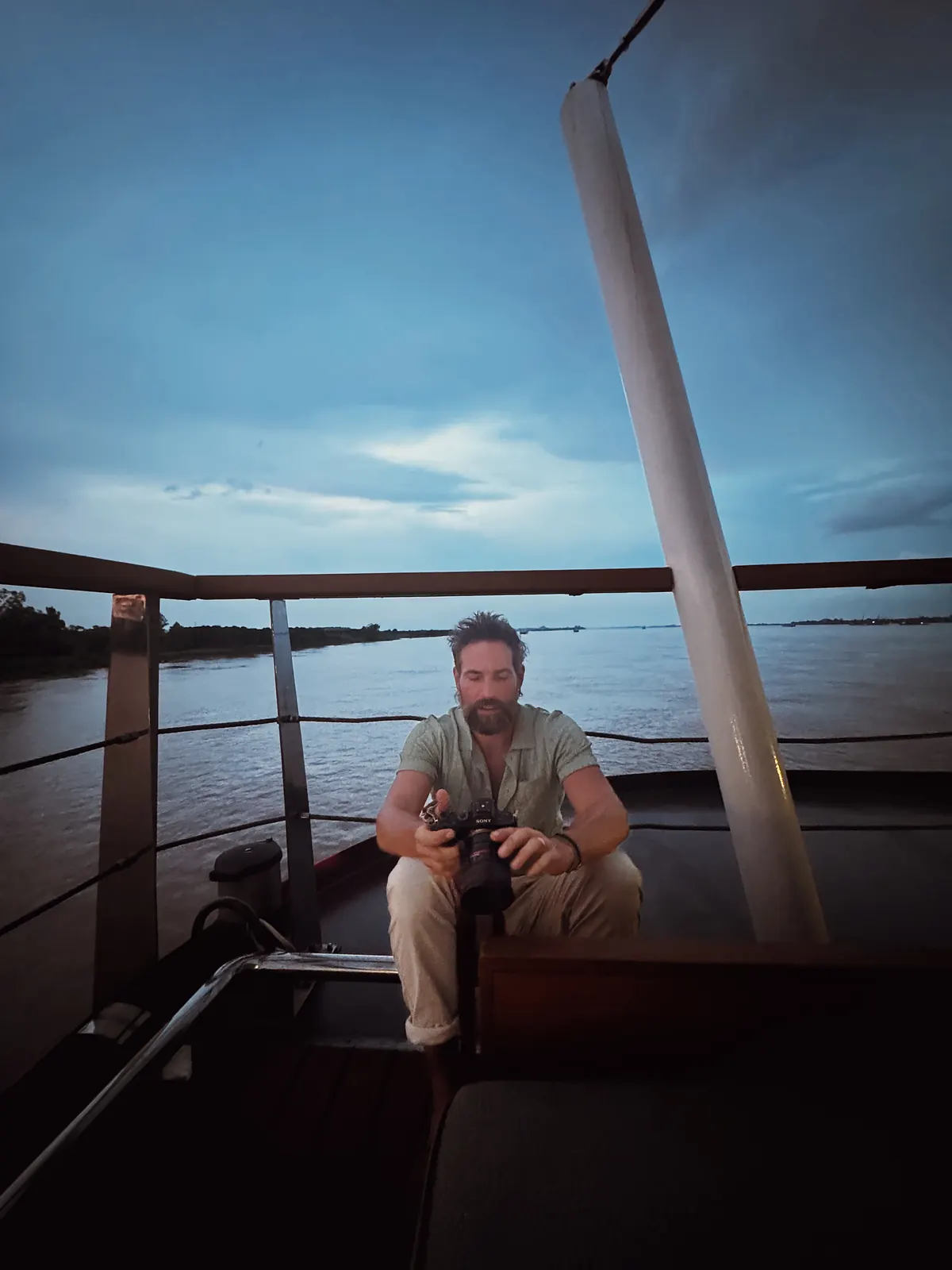 Matthew Nadu with his camera on a boat at dusk
